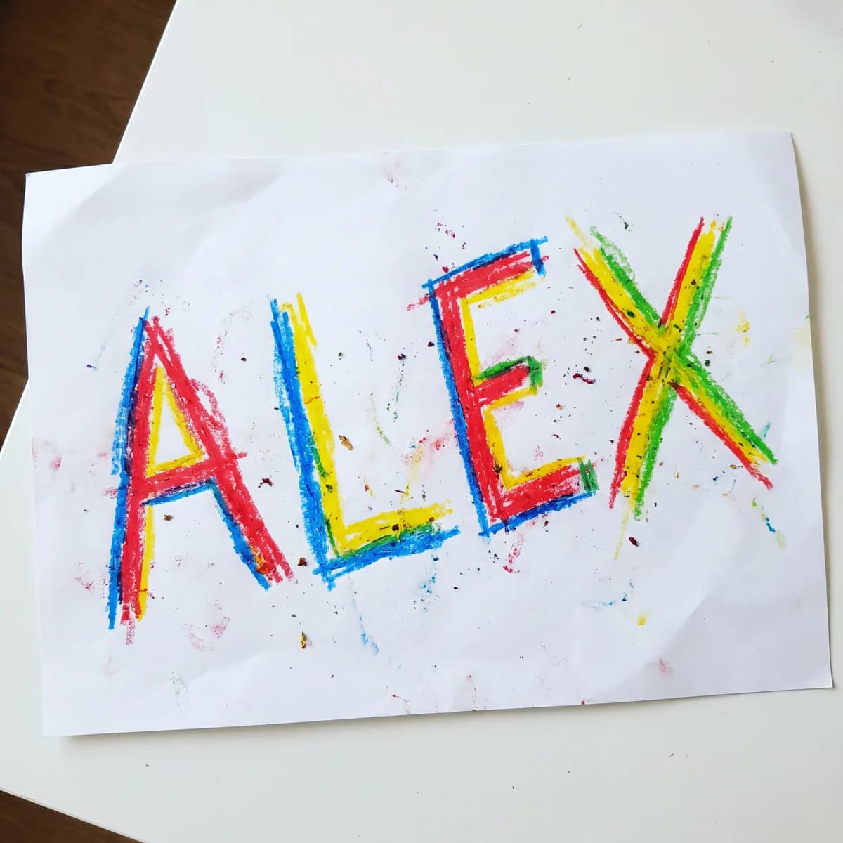 Child's wax crayon name drawing drawing on white paper, the kind PrintCraftMan turns into a UV-printed LED night light keepsake for godparent.